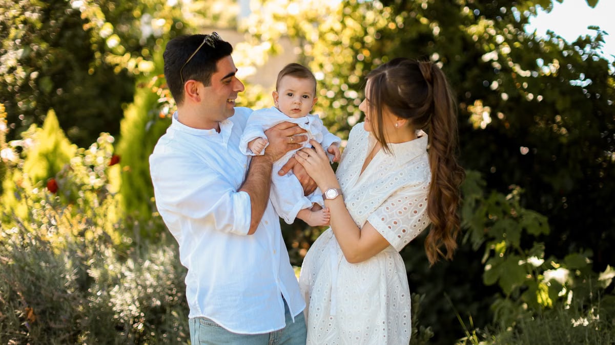 A joyful young family spending quality time together in a sunny outdoor park setting.